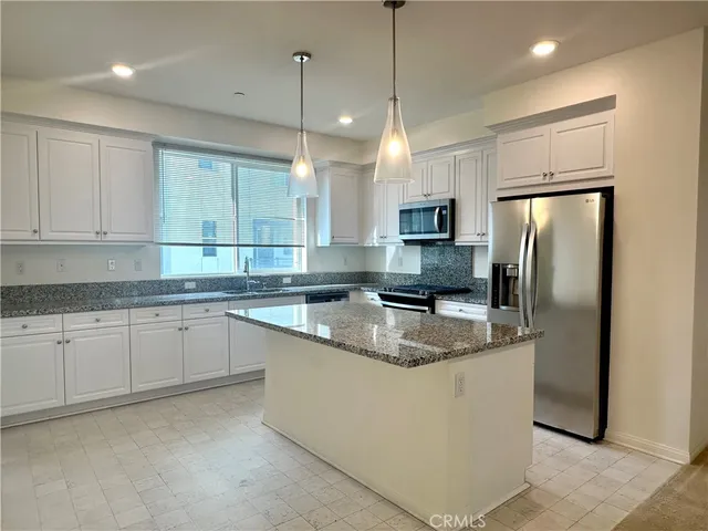 a kitchen with stainless steel appliances granite countertop a refrigerator a sink a stove a microwave and wooden cabinets