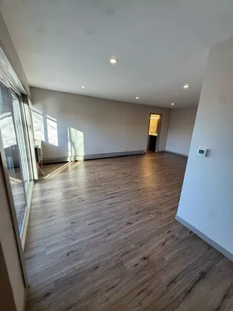 an empty room with wooden floor and entrance