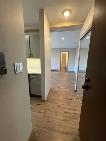a view of a hallway with wooden floor and a bathroom