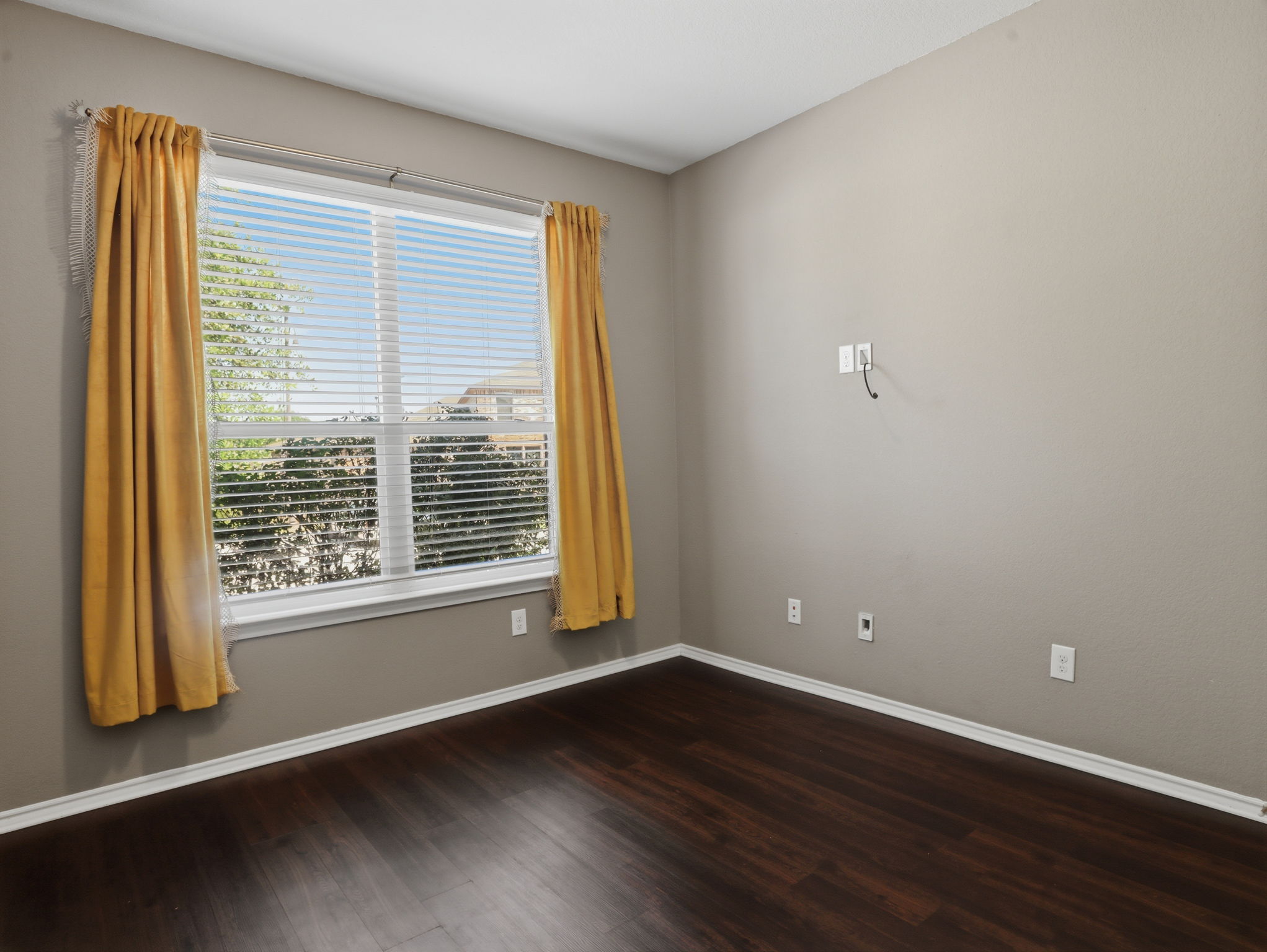 640 Landon Samuel Loop Pflugerville, TX 78660 - Photo 18 of 33 Room featuring wood-finish flooring, a large window with horizontal blinds, neutral wall paint, and white baseboards