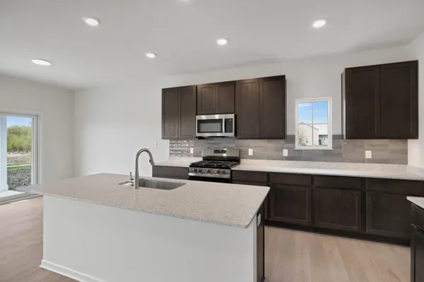 a kitchen with a sink and a stove top oven with wooden floor