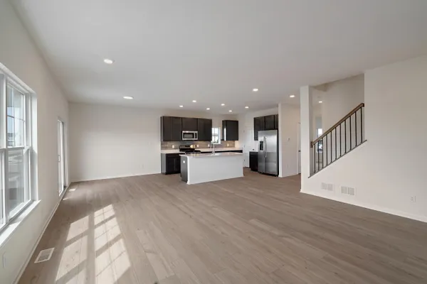 a view of kitchen with kitchen island wooden floor center island and stainless steel appliances