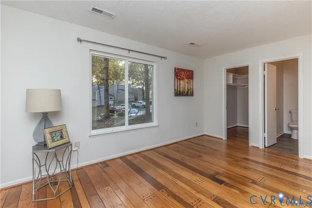 a view of an empty room with window and hardwood floor