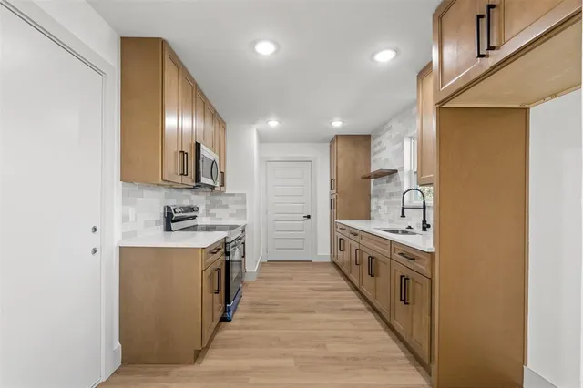 a large kitchen with stainless steel appliances granite countertop a lot of counter space and wooden floor