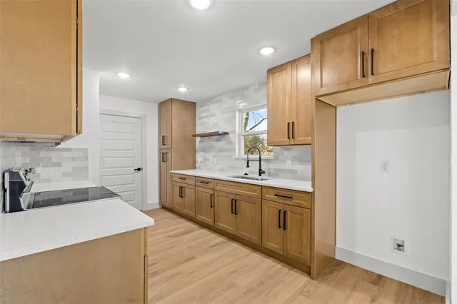 a large kitchen with a sink and dishwasher a refrigerator with wooden cabinets