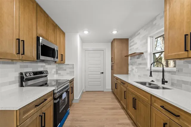 a kitchen with stainless steel appliances a sink a stove and cabinets
