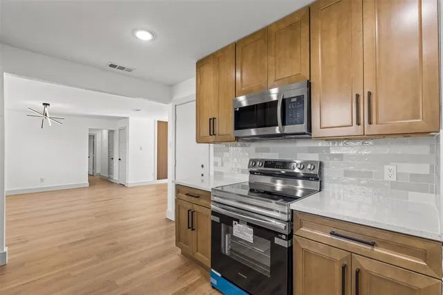 a kitchen with stainless steel appliances granite countertop a stove a sink and a microwave