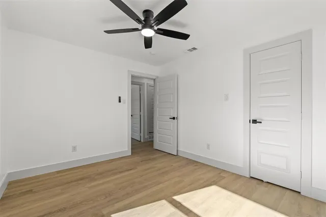 an empty room with wooden floor and ceiling fan