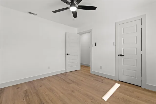 an empty room with wooden floor closet and windows
