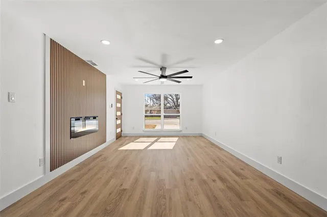 a view of an empty room with a window and wooden floor
