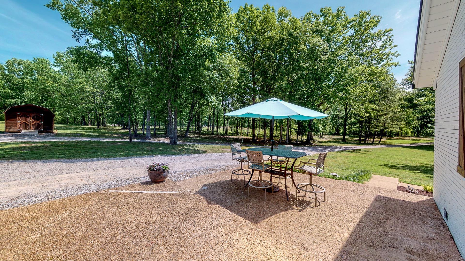 2361 Joe Brown Road Spring Hill, TN 37174 - Photo 22 of 27 a view of a table and chairs under an umbrella in backyard
