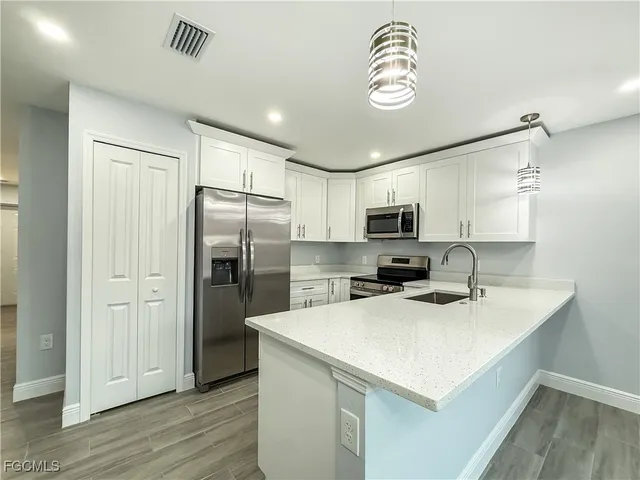 a kitchen with a refrigerator a sink cabinets and wooden floor