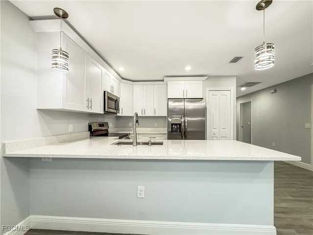 a large kitchen with stainless steel appliances a large counter top a stove and a refrigerator