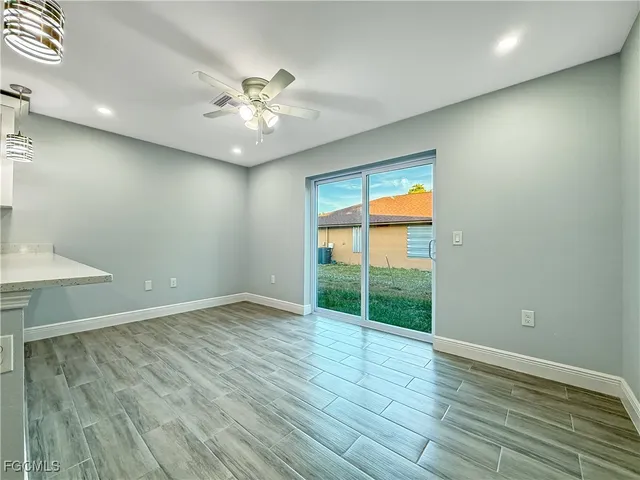 an empty room with wooden floor fan and windows