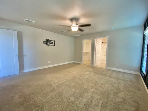 an empty room with windows and fan
