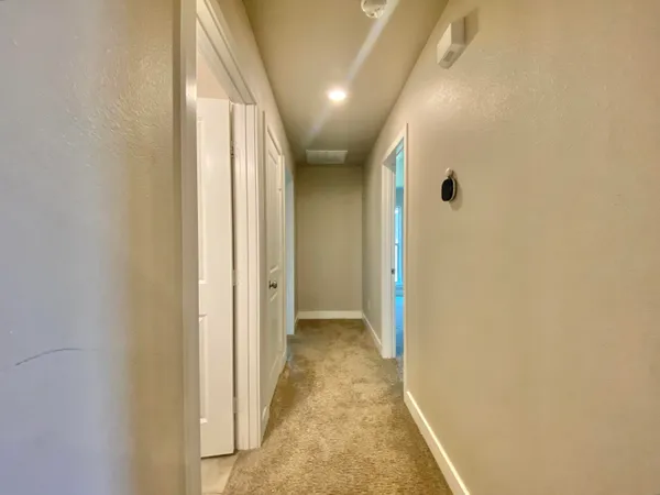 a view of a hallway with wooden floor and a bathroom