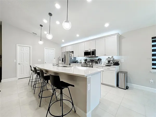 a kitchen with stainless steel appliances granite countertop a sink a stove a refrigerator cabinets and chairs