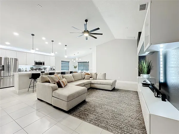 a living room with furniture kitchen view and a chandelier