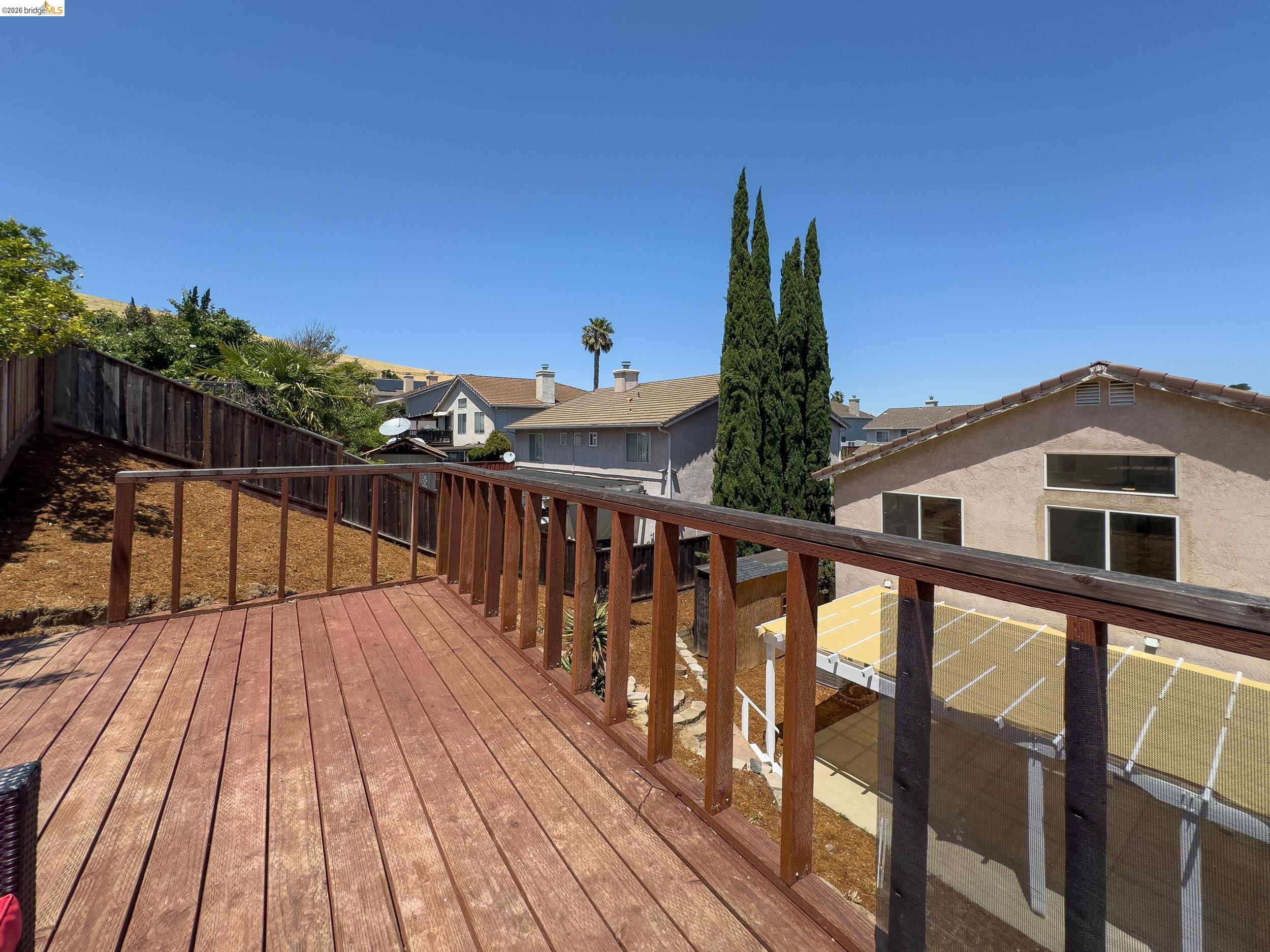 512 Burdick Drive Bay Point, CA 94565 - Photo 47 of 50 Spacious wood-planked deck with a matching wood railing, featuring a privacy fence and hillside landscaping