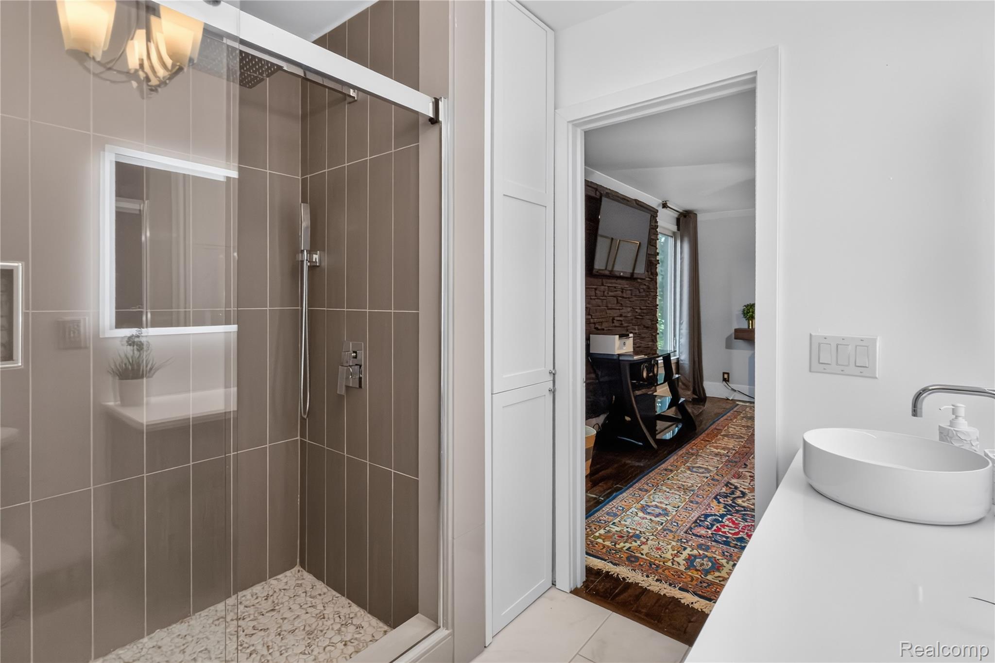 4860 Blue Bush Road Monroe, MI 48162 - Photo 31 of 59 Glass-enclosed shower with vertical taupe tiling, pebble-style shower floor, and brushed nickel fixtures