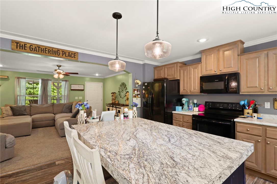 565 Valley Road Spruce Pine, NC 28777 - Photo 15 of 39 a kitchen with stainless steel appliances kitchen island granite countertop a refrigerator a stove top oven a sink dishwasher and white appliances with wooden floor