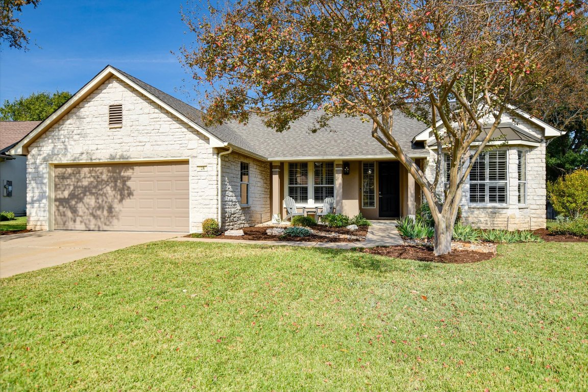 View of front of property with stone siding, roof with shingles, a porch, and a front lawn