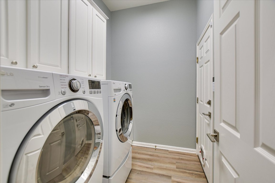 126 Bass Street Georgetown, TX 78633 - Photo 11 of 20 Laundry area with light wood finished floors, washer and clothes dryer, sink & cabinet space