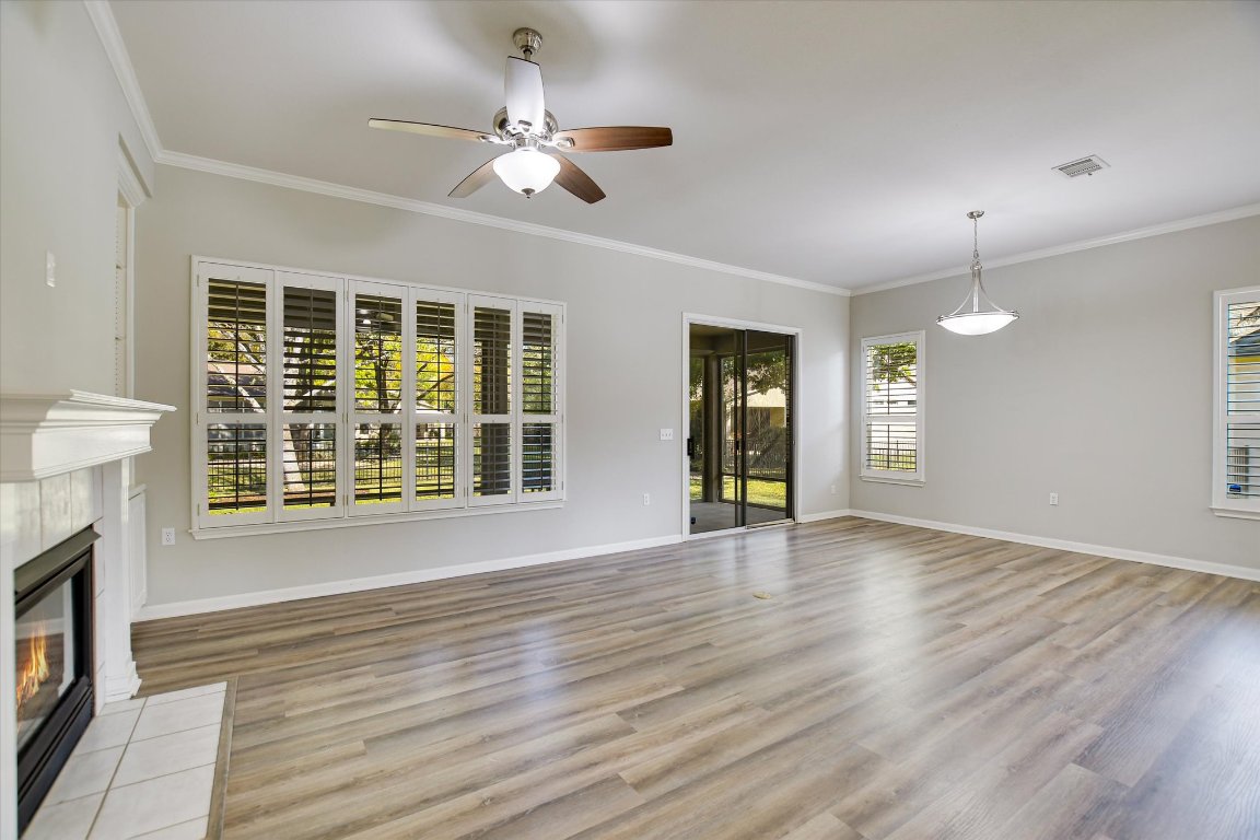 126 Bass Street Georgetown, TX 78633 - Photo 6 of 20 Unfurnished living room featuring crown molding, light wood-style floors, a tile fireplace, and a ceiling fan
