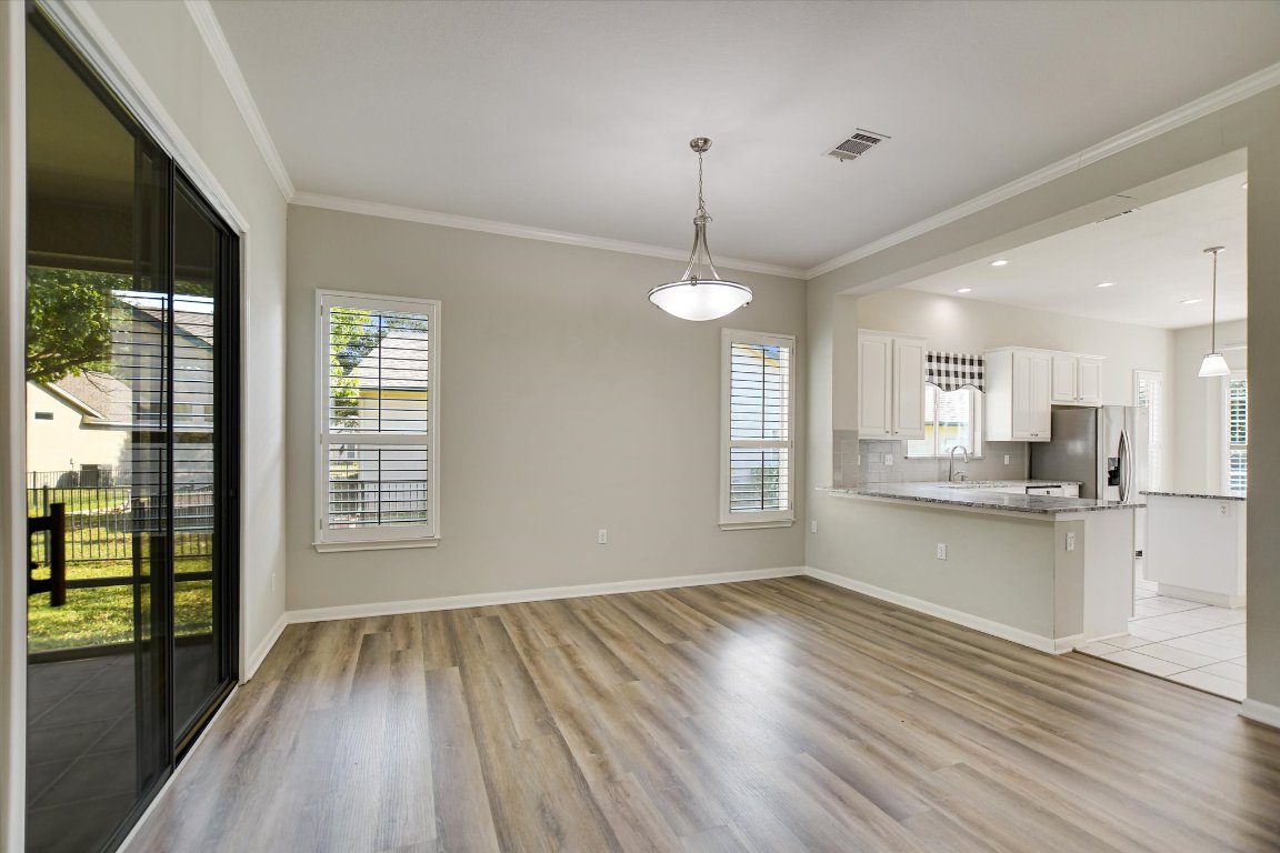 126 Bass Street Georgetown, TX 78633 - Photo 7 of 20 Kitchen with crown molding, white cabinetry, a peninsula, light wood finished floors, and stainless steel fridge with ice dispenser