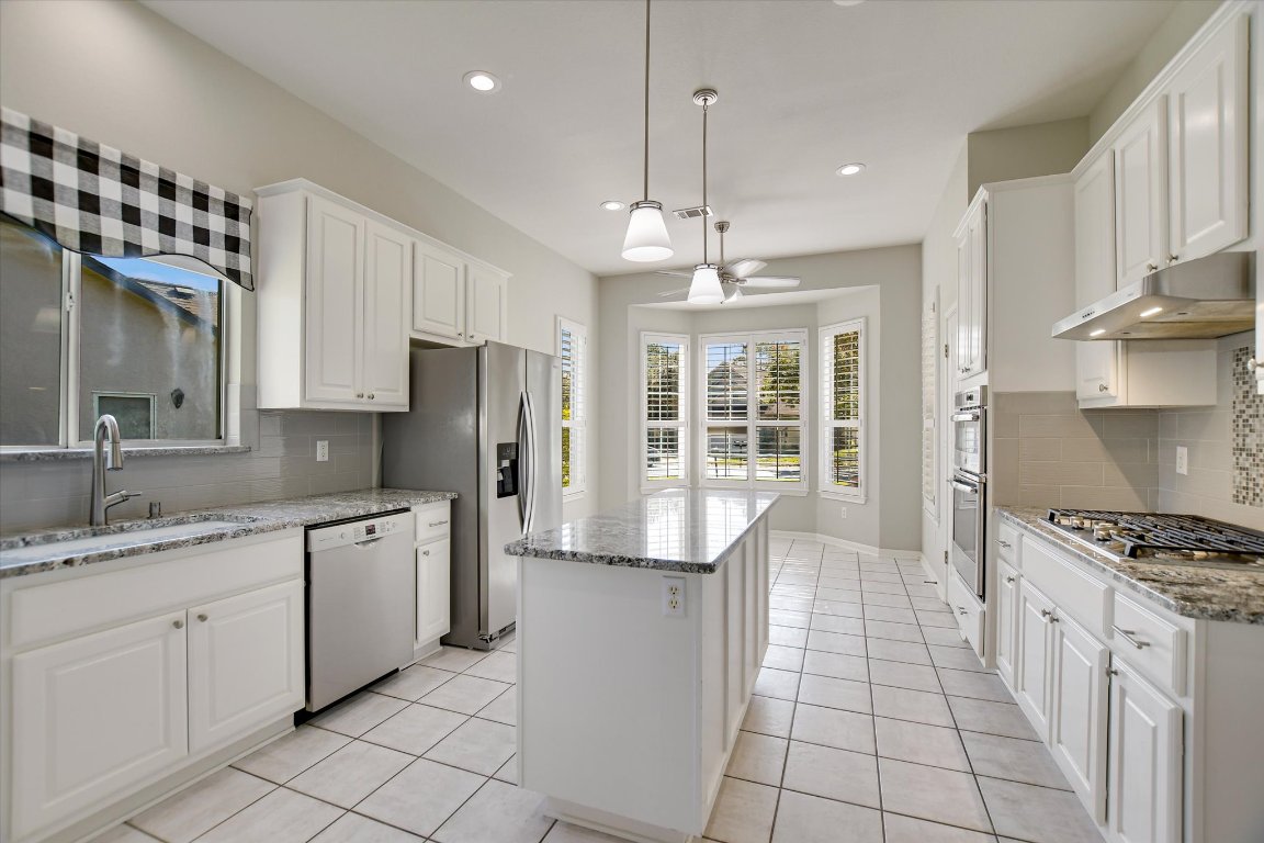 126 Bass Street Georgetown, TX 78633 - Photo 8 of 20 Kitchen featuring tasteful backsplash, white cabinetry, a center island, light stone countertops, and recessed lighting