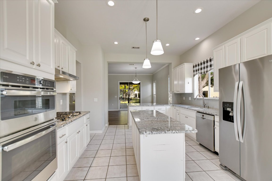 126 Bass Street Georgetown, TX 78633 - Photo 9 of 20 Kitchen with appliances with stainless steel finishes, pendant lighting, white cabinetry, light stone countertops, and recessed lighting