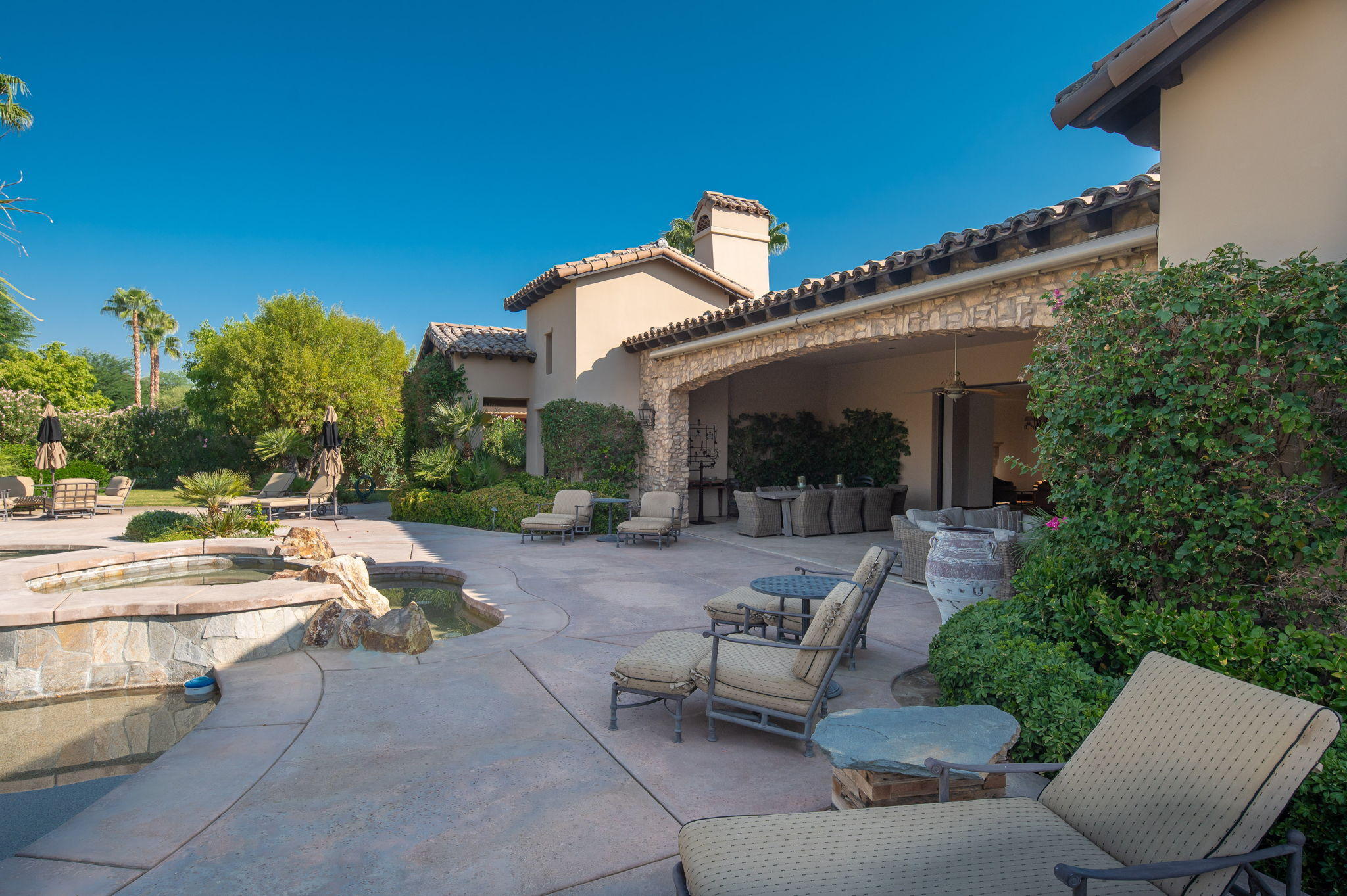 57325 Peninsula Lane La Quinta, CA 92253 - Photo 33 of 66 a view of a patio with couches table and chairs with potted plants and big yard
