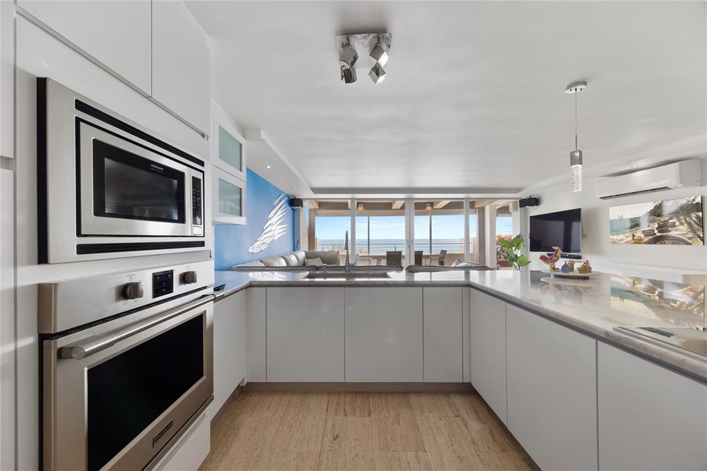 1 Bucaré, Unit 4 San Juan, PR 00913 - Photo 10 of 49 a kitchen with stainless steel appliances a sink dishwasher a stove and a microwave oven on granite countertops