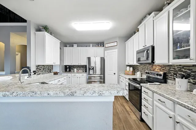 a kitchen with stainless steel appliances granite countertop a sink stove microwave and refrigerator