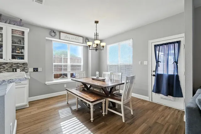 a dining room with wooden floor a chandelier a wooden table and chairs