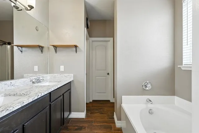 a bathroom with a granite countertop sink and a bathtub