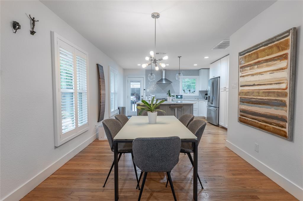 864 Peavy Road Dallas, TX 75218 - Photo 6 of 21 Dining area with wood-finish flooring, white plantation shutters, and a contemporary chandelier