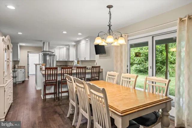 a dining room with wooden floor a chandelier a wooden table and chairs