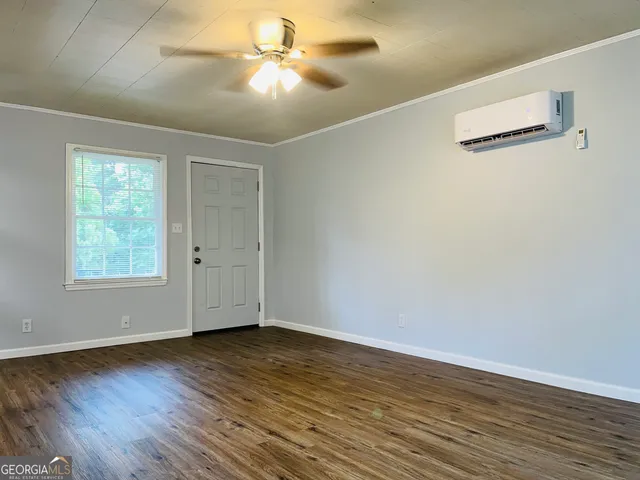 an empty room with wooden floor fan and windows