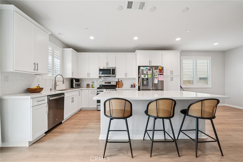 14270 Hercules Street Hesperia, CA 92345 - Photo 23 of 46 a kitchen with stainless steel appliances granite countertop a dining table chairs stove and white cabinets