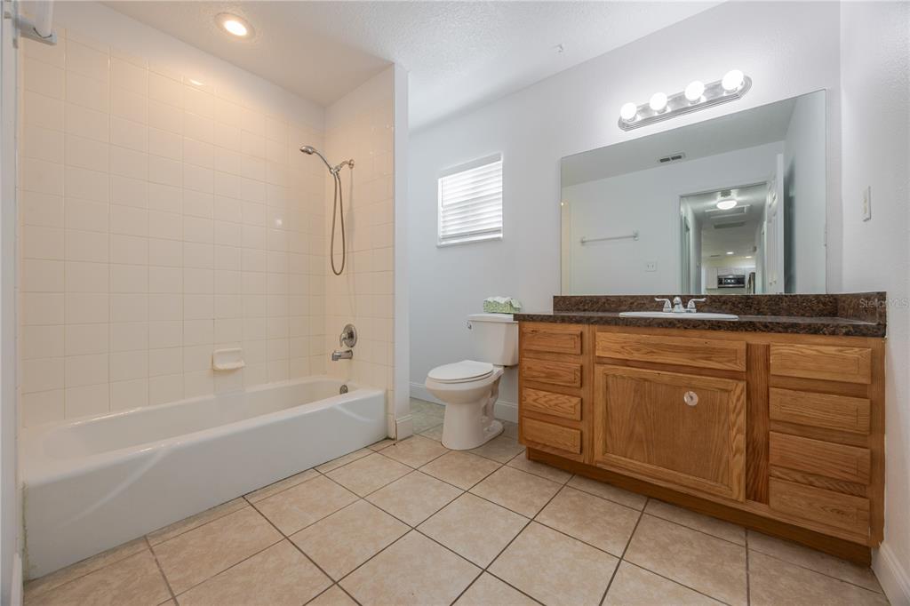 495 Orange Avenue St. Cloud, FL 34769 - Photo 22 of 32 a spacious bathroom with a granite countertop sink a toilet mirror and a bathtub