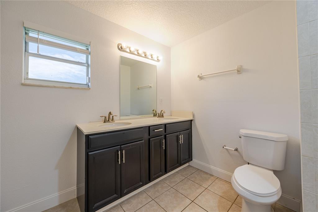 495 Orange Avenue St. Cloud, FL 34769 - Photo 27 of 32 a bathroom with a toilet a sink and mirror