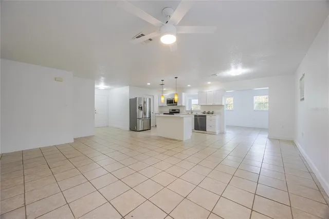 a view of kitchen and empty room with wooden floor