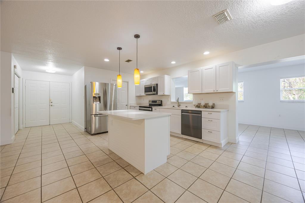 495 Orange Avenue St. Cloud, FL 34769 - Photo 10 of 32 a kitchen with stainless steel appliances kitchen island granite countertop a sink and cabinets