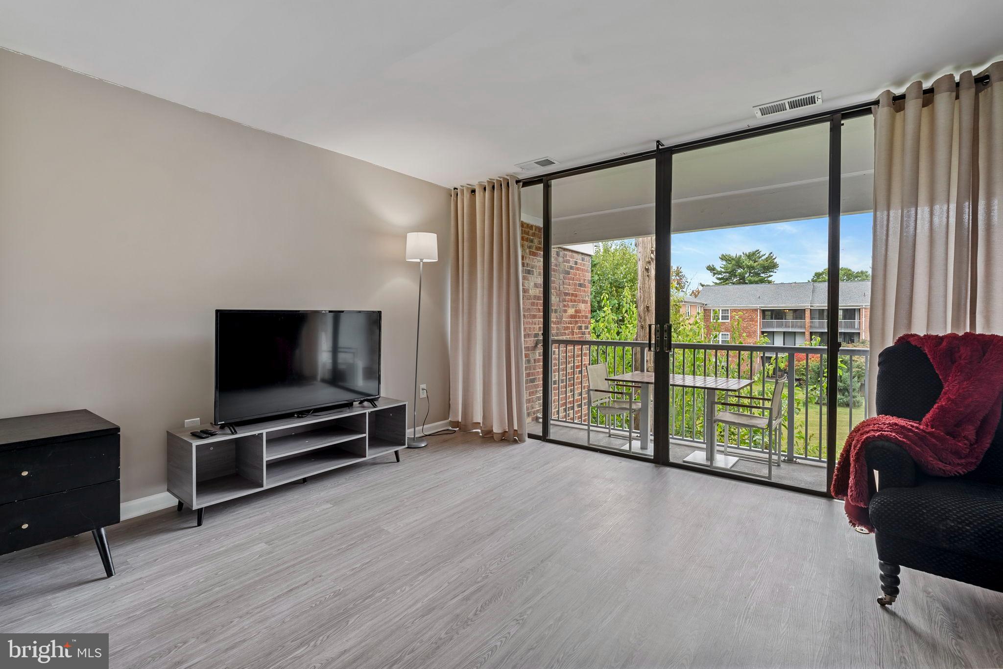 790 Quince Orchard Boulevard, Unit 202 Gaithersburg, MD 20878 - Photo 21 of 25 Bright and airy living space with balcony view.
