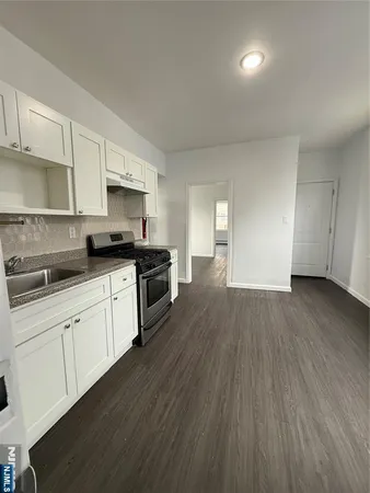 a kitchen with granite countertop a sink cabinets and wooden floor
