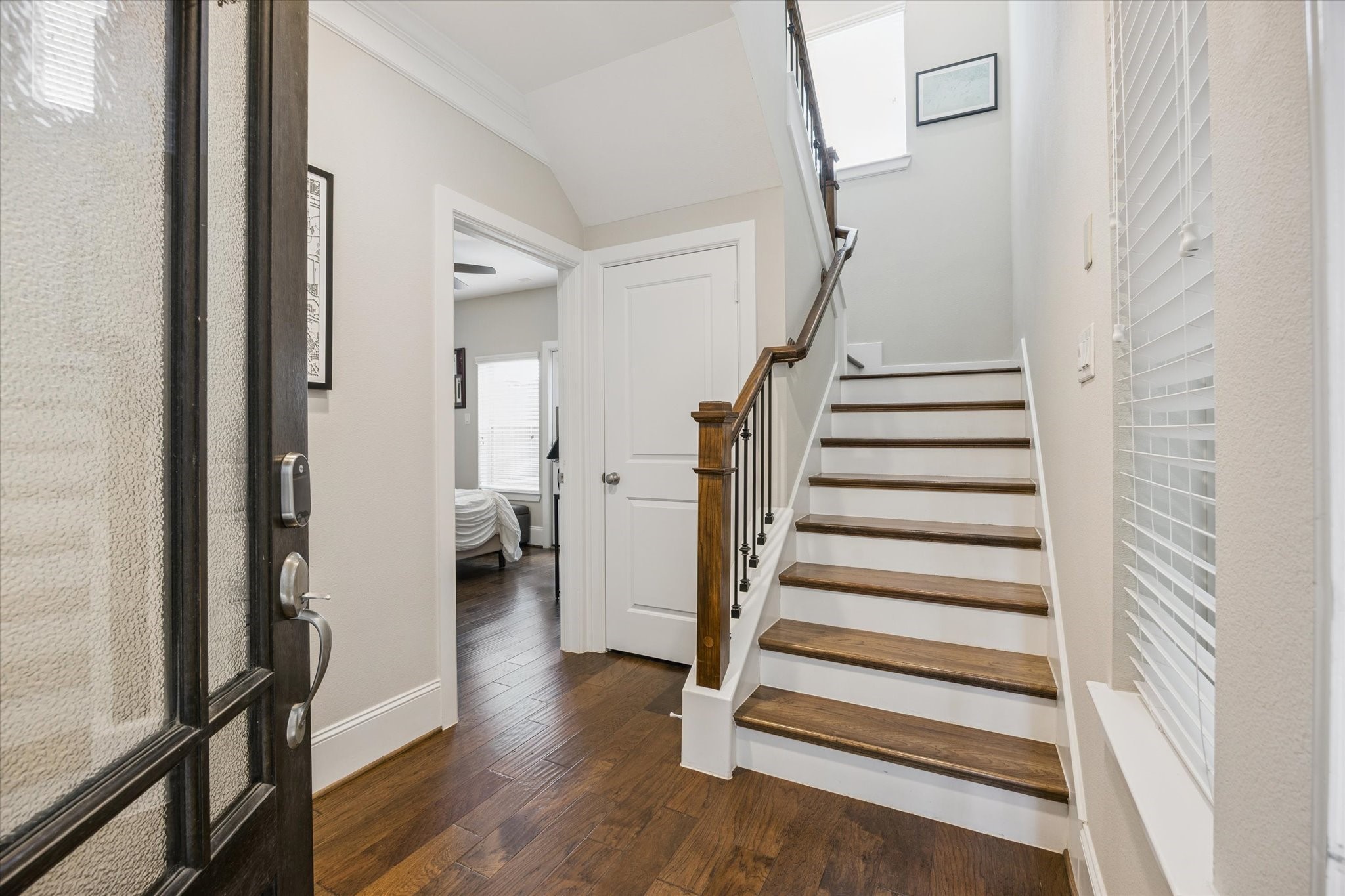 739 Dorothy Street Houston, TX 77007 - Photo 4 of 30 Welcome guests with a bright and airy entryway featuring rich wood floors, crisp white trim, and an open staircase with wrought-iron balusters. Natural light pours in through the window above, and a private first-floor bedroom is tucked just off the foyer.