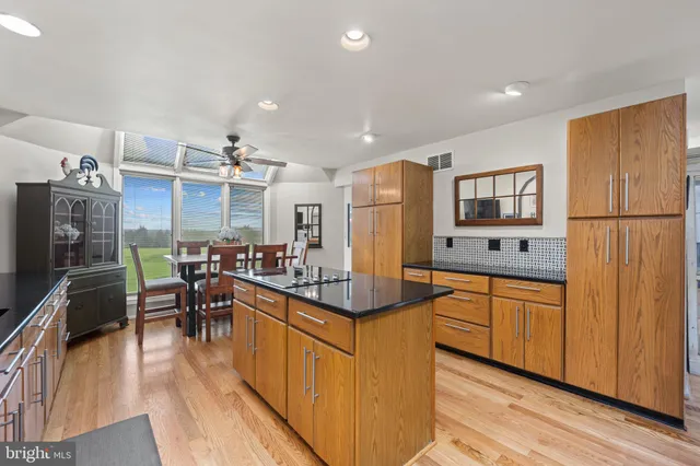a kitchen with stainless steel appliances kitchen island granite countertop a refrigerator a stove top oven a sink dishwasher and dining table with wooden floor