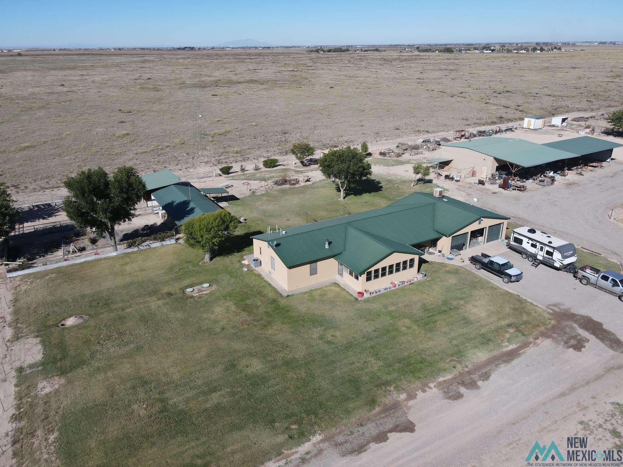 6660 Cherokee Road Dexter, NM 88230 - Photo 37 of 46 Expansive property featuring a single-story residence with a green metal roof, a multi-car garage, and an additional detached structure with a matching green metal roof