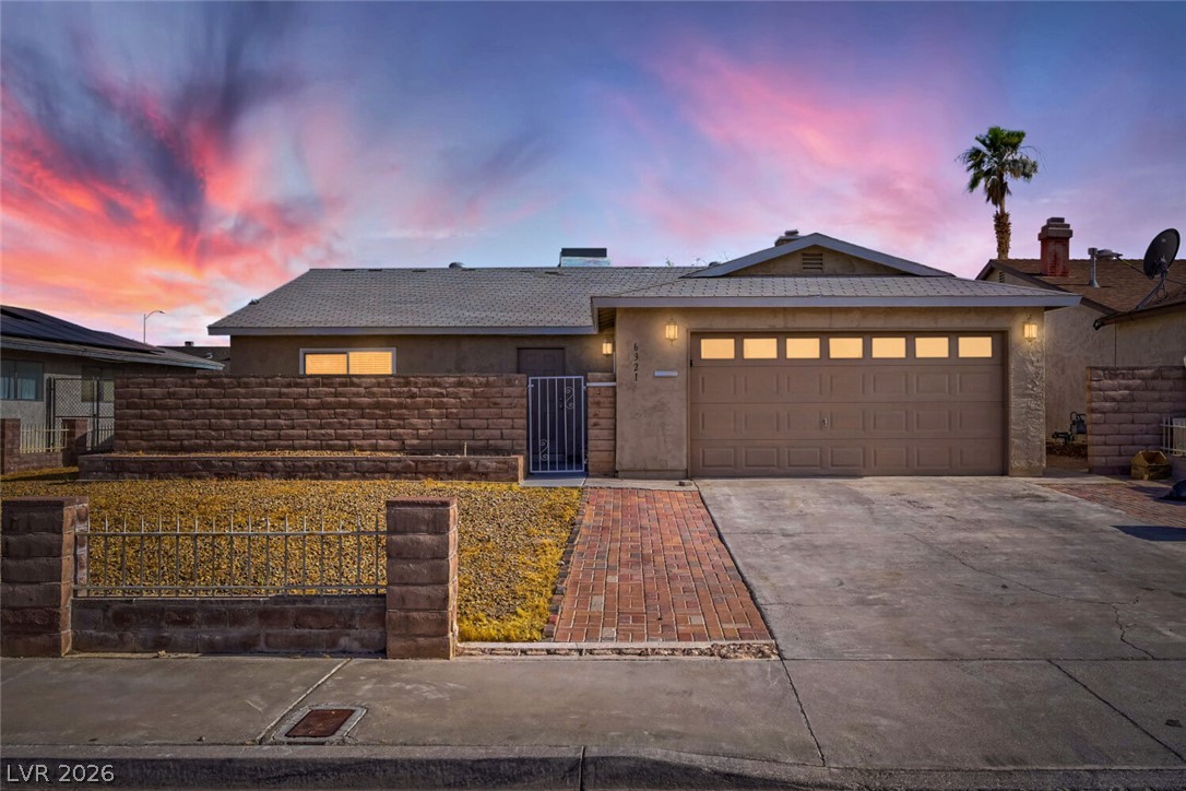 6321 Portola Road Las Vegas, NV 89108 - Photo 4 of 29 A striking desert landscape property boasting a garage, mature palm, and a captivating sunset.